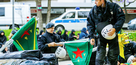 Polizeibeamte kontrollieren die Fahnen bei einer kurdischen Demo...