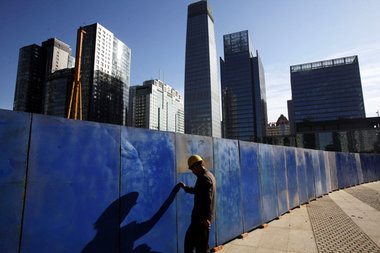 Arbeiter vor Bauzaun in Peking. Neben sinkenden Exporten droht C...