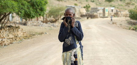 Eine Frau in Tigray versucht sich vor dem Leichengeruch, der ihr... Eine Frau in Tigray versucht sich vor dem Leichengeruch, der ihr...