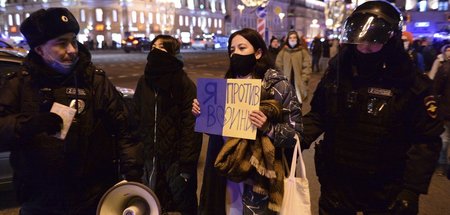 Polizisten halten Demonstrantin fest, auf deren Plakat es heißt