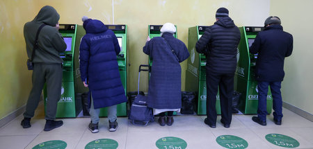 Sanktionen gegen große russische Banken: Menschen an Geldautomat...