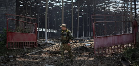 Eine ukrainische Einsatzkraft vor einer zerstörten Lagerhalle na...