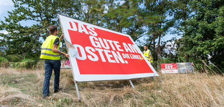 Arbeiter bauen nach der Landtagswahl in Sachsen ein Wahlplakat d...