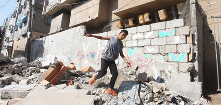 Ein palästinensischer Junge geht über die Trümmer seines Hauses,