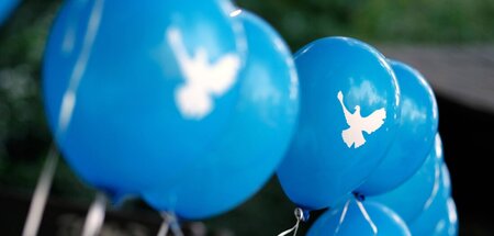 Aufgereihte Luftballons mit dem Symbol einer Friedenstaube anläs...