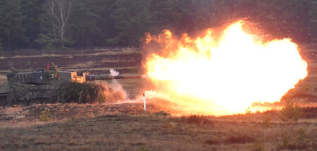 Ein Kampfpanzer vom Typ Leopard 2 feuert einen scharfen Schuß au...