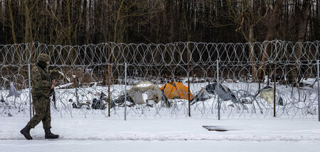 Polnischer Grenzsoldat neben einem Zeltcamp von Geflüchteten auf...