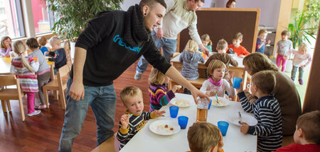 Männliche Erzieher im ersten Lehrjahr betreuen Kinder beim Mitta...