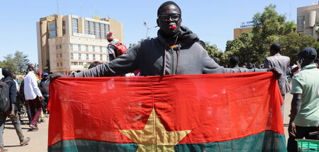 Ein Mann mit der Flagge Burkina Fasos in der Hauptstadt Ouagadou