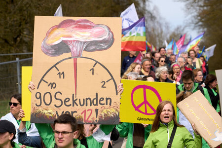 Teilnehmer des Ostermarsches 2023 laufen am Zaun des Bundeswehr-...