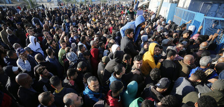 Menschen stehen vor einer Verteilstelle von UNRWA nach Mehl an (