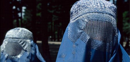 Zwei vollverschleierte afghanische Frauen, die ihre Kinder in Un...