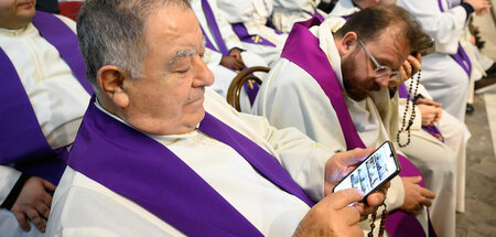 Kritisch prüfen: Ein Priester betrachtet bei einer Trauerfeier f...