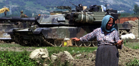 Vor Drohkulisse: Eine albanische Frau spinnt Wolle nahe der Luft...