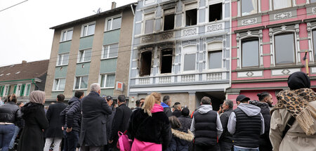 Trauernde stehen vor dem ausgebrannten Haus, in dem das mutmaßli... Trauernde stehen vor dem ausgebrannten Haus, in dem das mutmaßli...