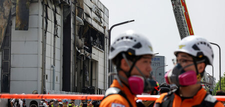 Unter Schock: Hilfskräfte nach dem Fabrikinferno, das zahlreiche...