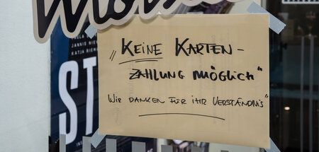 Wo keine Kartenzahlungen möglich ist, gucken Asylsuchende mit Be...