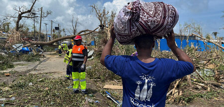 Ein Mann trägt seine Habseligkeiten, während Rettungskräfte eine...