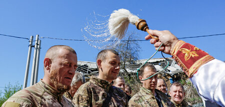 Ein Priester segnet russische Soldaten mit Weihwasser während de...
