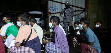 Arbeiter aus Bangladesch warten mit ihren Pässen in der Hand wäh...