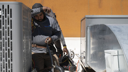 Bei extremer Hitze: Arbeiter installiert eine Klimaanlage