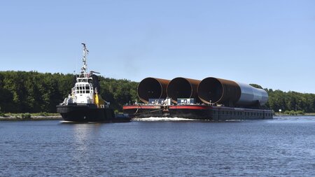 Werktag auf dem Kanal: Schlepper fährt mit Monopile-Fundamenten ... Werktag auf dem Kanal: Schlepper fährt mit Monopile-Fundamenten ...