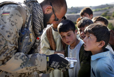 Viele Knöpfe: Ein deutscher NATO-Soldat zeigt afghanischen Kinde...