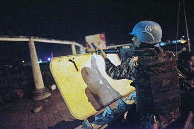 Schnellfeuergewehr im Anschlag: UN-Blauhelmsoldat in der Nacht
z...