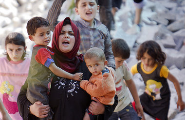 Auf ihrem R&uuml;cken: Eine syrische Mutter ist mit ihren Kinder...