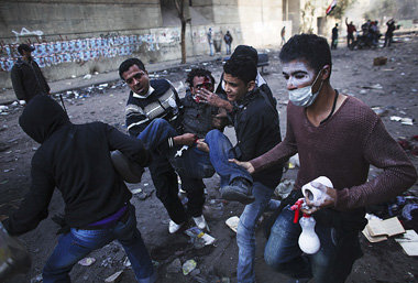 Ein Verletzter wird von Demonstranten in Kairo in Sicherheit geb...