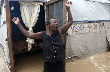 Eine verzweifelte Frau steht vor ihrem überfluteten Zelt in eine...