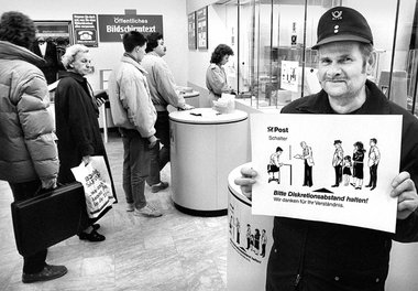 Ein Postmitarbeiter zeigt 1988 in Hamburg den Wartenden vorm Sch...