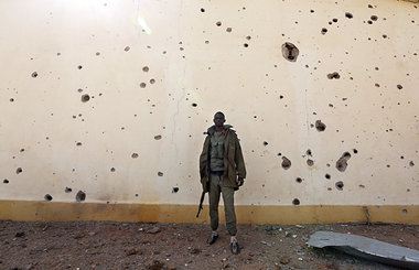 Malischer Soldat vor einer Wand mit Einschu&szlig;l&ouml;chern i...