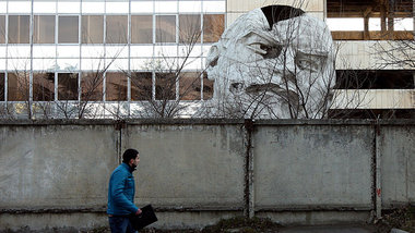 Zerst&ouml;rtes Lenin-Monument vor einer geschlossenen Fabrik in...