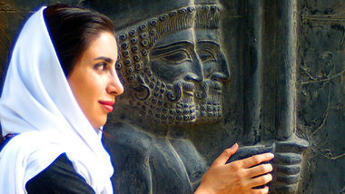 Iranische Frau vor einem antiken Relief in Persepolis, das zwei ... Iranische Frau vor einem antiken Relief in Persepolis, das zwei ...
