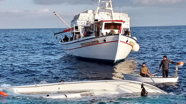 Fischer neben einem gekenterten Fl&uuml;chtlingsboot am Montag v...
