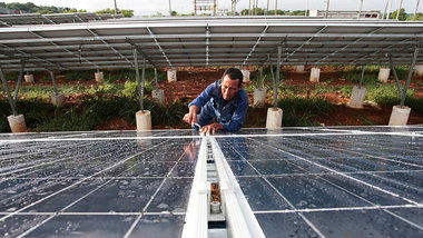 Ein Arbeiter justiert Solarpaneele in einem Park in Havannas Au&... Ein Arbeiter justiert Solarpaneele in einem Park in Havannas Au&...