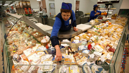 Alles Käse: Eine Verkäuferin arrangiert Milchprodukte ... Alles Käse: Eine Verkäuferin arrangiert Milchprodukte ...
