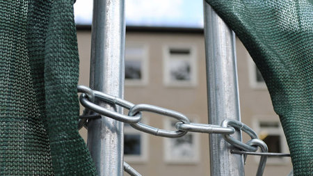 Eine Kette mit Vorhängeschloß hängt am Zaun der ... Eine Kette mit Vorhängeschloß hängt am Zaun der ...