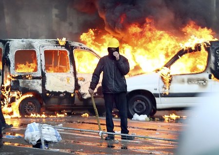 Ein Demonstrant vor einem brennenden Auto am Donnerstag in Brüss...