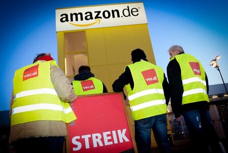 Streikende stehen vor der Betriebsstätte des Online-Händlers Ama...
