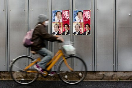 Ein Mann fährt an Wahlkampfplakaten der regierenden Liberaldemok...