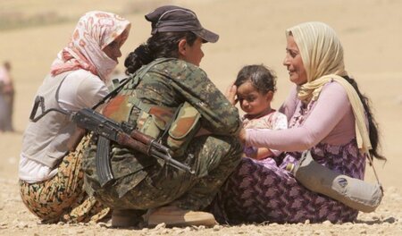 Eine Kämpferin der kurdischen YPG unterstützt geflüchtete Jesidi...