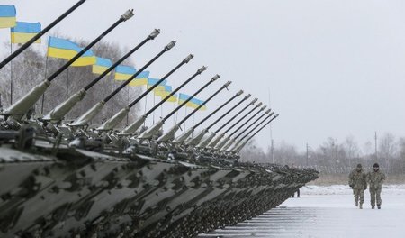 Ukrainische Militärs vor einer Reihe von Transportpanzern auf de...