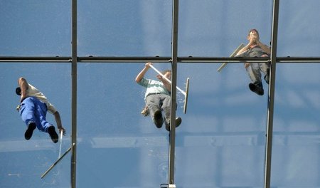 Unterbezahlt und gestresst: Gebäudereinger putzen Fenster des Ho...