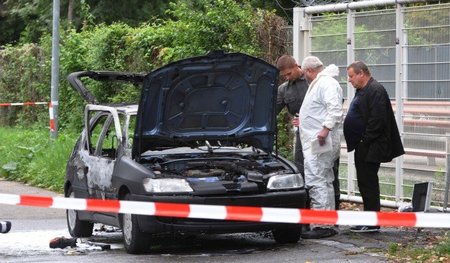 Kriminaltechniker untersuchen den ausgebrannten Wagen Florian He...