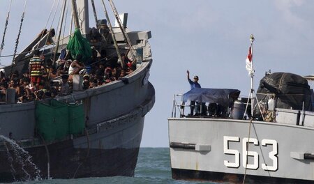 Auf hoher See: Ein myanmarischer Marinesoldat gibt einem Boot mi... Auf hoher See: Ein myanmarischer Marinesoldat gibt einem Boot mi...