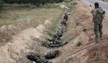 Ein Kämpfer der Al-Nusra-Front inspiziert die Leichen zuvor ermo... Ein Kämpfer der Al-Nusra-Front inspiziert die Leichen zuvor ermo...