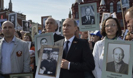 Wladimir Putin mit einem Porträt seines Vaters während eines Ged...