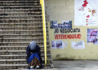 Pristina am 1. Februar: Bettlerin neben der Losung »Keine Verhan...